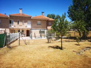 una casa con un patio con un árbol delante en Agradable casa con jardín: Casasola, en San Cristóbal de Segovia