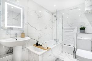 a white bathroom with a sink and a tub at Luxury 3 Bedroom Apartment in Marylebone in London