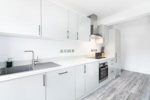 een witte keuken met witte kasten en een wastafel bij Luxury 3 Bedroom Apartment in Marylebone in Londen