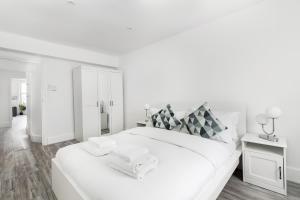 een witte slaapkamer met een groot wit bed met handdoeken erop bij Luxury 3 Bedroom Apartment in Marylebone in Londen