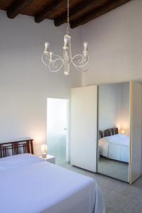 een slaapkamer met een wit bed en een kroonluchter bij Casale Manca - Luxury Country House - The quiet with a sea view in Licata