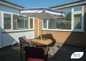 a table and chairs with an umbrella on a patio at Luke Stays - Cheveley Park in Leamside