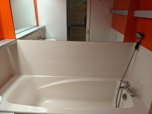 y baño con bañera blanca y espejo. en Studio rénové centre station Vallandry, en Landry