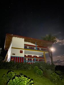 un edificio de noche con una palmera delante en Cabaña Filo de Oro, jardín en Jardin