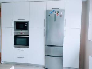 a white kitchen with a refrigerator and a microwave at La Ola de Cantabria in Miengo