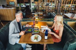 a man and woman sitting at a table in a restaurant at Llanerch Vineyard Hotel in Hensol