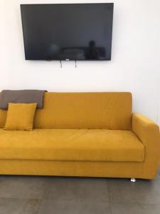 Sofá amarillo con TV en la pared en La Casa al Gelso en Rodi Garganico