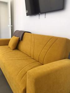 a yellow couch with a television on a wall at La Casa al Gelso in Rodi Garganico