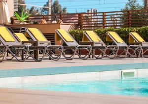 een rij gele ligstoelen naast een zwembad bij KAKTUS Hotel Volga - Adults Recommended in Calella