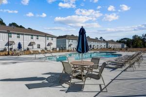 uma mesa e cadeiras com um guarda-sol em frente a uma piscina em LUXURY TOWNHOME NEAR DOWNTOWN AND PENSACOLA BEACH em Pensacola