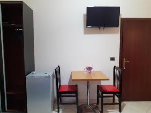 a small table and chairs with a television on a wall at Hotel Shpetimi in Çorovodë