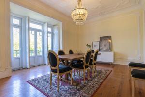 una sala da pranzo con tavolo, sedie e lampadario pendente di Saldanha Charming Palace a Lisbona