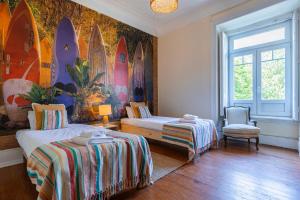 リスボンにあるSaldanha Charming Palaceのベッド2台とサーフボードの壁画が備わる客室です。