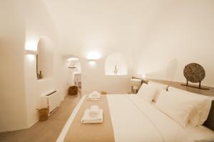 una camera da letto con un grande letto bianco con cuscini bianchi di Cydonia Caves a Megalochori