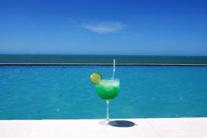a green drink in a glass next to a swimming pool at Bruno Marambaia Charme Hotel in Beberibe