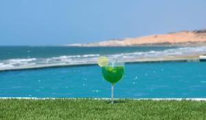 a glass of green drink with a lime in front of a pool at Bruno Marambaia Charme Hotel in Beberibe