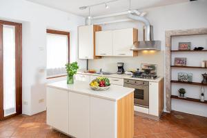 a kitchen with white cabinets and a bowl of fruit on a counter at COUNTRYHOUSE NOCINO - Regarda Travel in Lazise