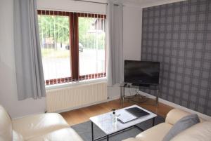 a living room with a white couch and a tv at Kelpies Serviced Apartments- McLaughlan in Falkirk