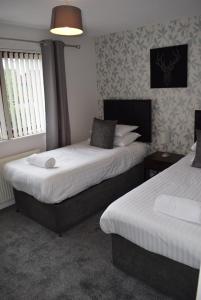 a bedroom with two beds and a lamp and windows at Kelpies Serviced Apartments- McLaughlan in Falkirk +5 photos