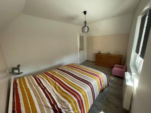 ein Schlafzimmer mit einem Bett mit einer bunten gestreiften Decke in der Unterkunft Agréable maison 3* en bord de mer in Dieppe