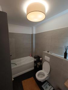 y baño con aseo blanco y bañera. en Apartament rafinat cu grădină privată, en Floreşti