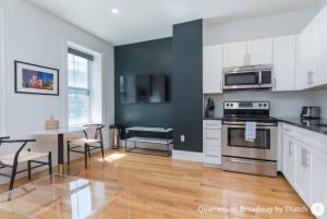 a kitchen with white cabinets and a table with chairs at West Broadway Quarters by Thatch in Boston