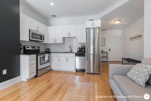 a kitchen with white cabinets and a stainless steel refrigerator at West Broadway Quarters by Thatch in Boston