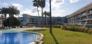 a resort with a pool and palm trees and a building at Sun & Relax in Denia Beach in Denia