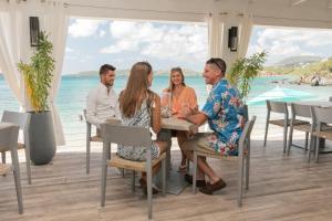 a group of people sitting around a table at the beach at Secret Harbour Beach Resort in Nazareth