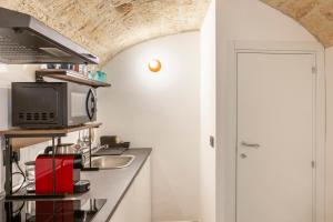 una cucina con bancone, forno a microonde e lavandino di Just Here apartments - Lascia Fare a Dio a Bari