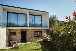 uma casa com janelas de vidro e um quintal em Casa da Vila - Pool & Hot Tub with Mountain View in Gerês em Terras de Bouro