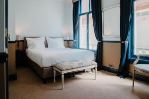 a bedroom with a bed and a bench and windows at Paleis Hotel in The Hague