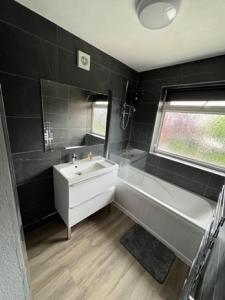 a bathroom with a white sink and a tub and a window at Serene Property Next to Southampton General Hospital in Southampton