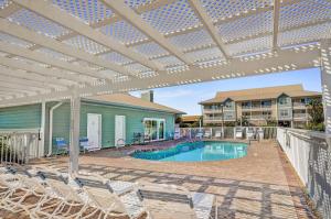 a patio with chairs and a swimming pool with a pergola at St Martin Beachwalk Villas 432 in Destin