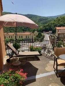 einen Balkon mit einem Sonnenschirm, einem Tisch und Stühlen in der Unterkunft Logis Hotel Restaurant Le Bellevue in Prats-de-Mollo-la-Preste