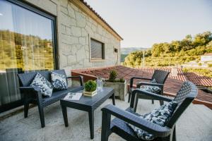 eine Terrasse mit Stühlen, einem Tisch und einem Sofa in der Unterkunft Casa da Adega - Quinta da Portela in Terras de Bouro