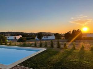 a villa with a swimming pool at sunset at Herdade do Gizo - Casa Reis in Cuba
