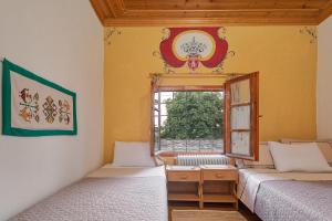 two beds in a room with a window at Archontiko Rapti Stone Traditional House in Monodendri