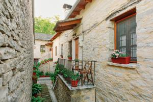モノデンドリにあるArchontiko Rapti Stone Traditional Houseのテーブルと椅子が置かれたバルコニーのある石造りの建物