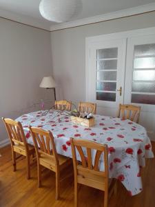 une table à manger avec un tissu de table blanc et des fleurs rouges dans l'établissement Apigîte68, proche route des vins, Vosges, Colmar et non loin d'Europa-Park!, à Ostheim