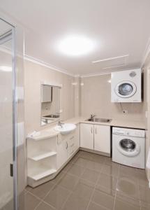a white bathroom with a sink and a washing machine at Apartments on Palmer in Rockhampton