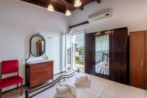 een slaapkamer met een spiegel en een rode stoel bij Aroni Cretan comfortable house - Hamam suites Aroni in Arónion