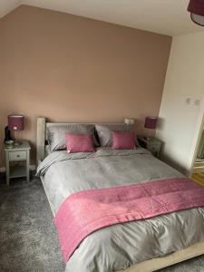 a bedroom with a large bed with two pink pillows at Marie's Hoose in Stornoway
