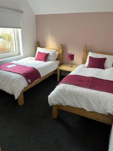 a bedroom with two beds and a window at Marie's Hoose in Stornoway