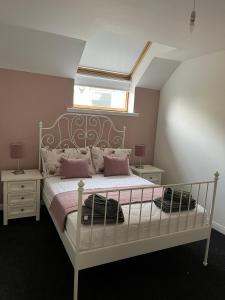 a bedroom with a white bed with pink pillows at Marie's Hoose in Stornoway