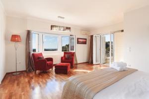 a bedroom with a bed and two chairs and windows at Villa Amarandes With Private Pool in Paradeísion +30 photos