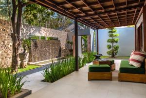 an outdoor patio with green furniture and a brick wall at The Chandi Boutique Resort & Spa in Senggigi