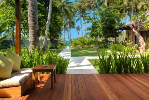 a wooden deck with a couch and a table at The Chandi Boutique Resort & Spa in Senggigi