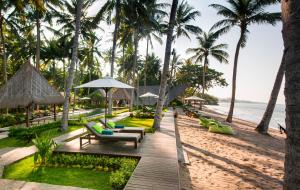 a resort with chairs and palm trees on the beach at The Chandi Boutique Resort & Spa in Senggigi