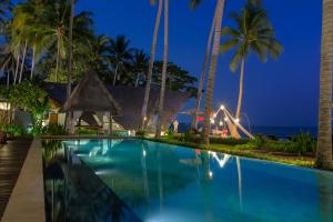 a swimming pool at night with the ocean in the background at The Chandi Boutique Resort & Spa in Senggigi